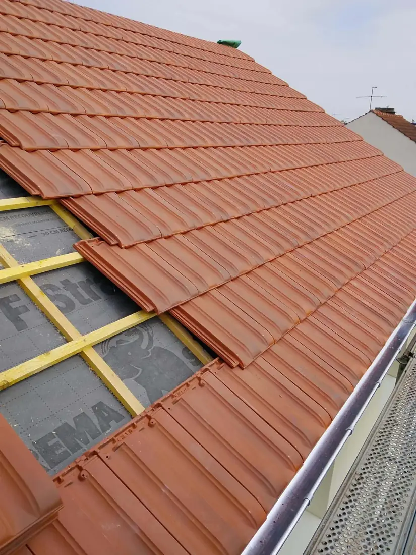 Pose de tuiles rouges neuves en bas de pente avec gouttière